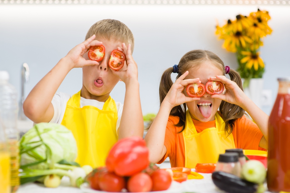 Happy kids having fun with food vegetables at kitchen holds toma