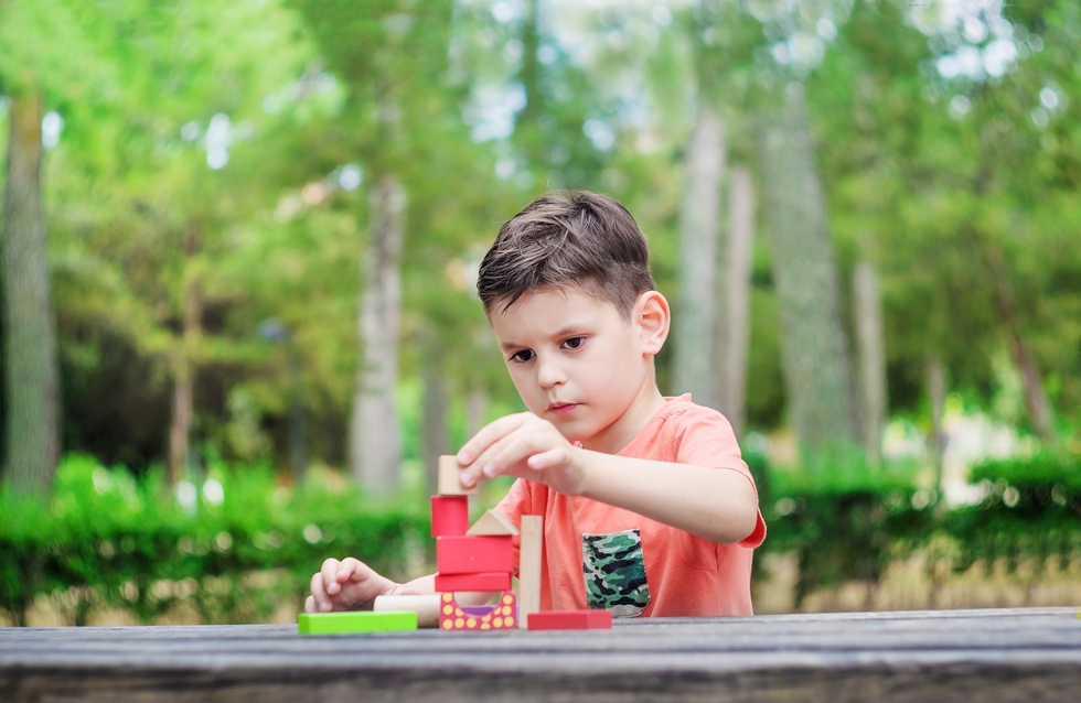 Preschool child build a tower of colorful wooden building blocks