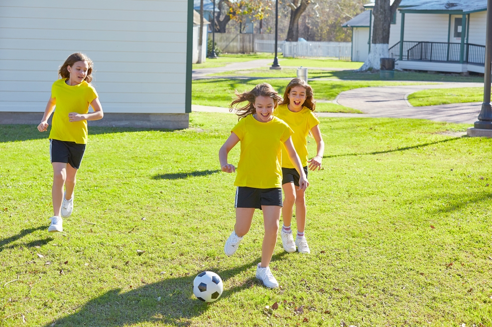 Friend girls teens playing football soccer in a park