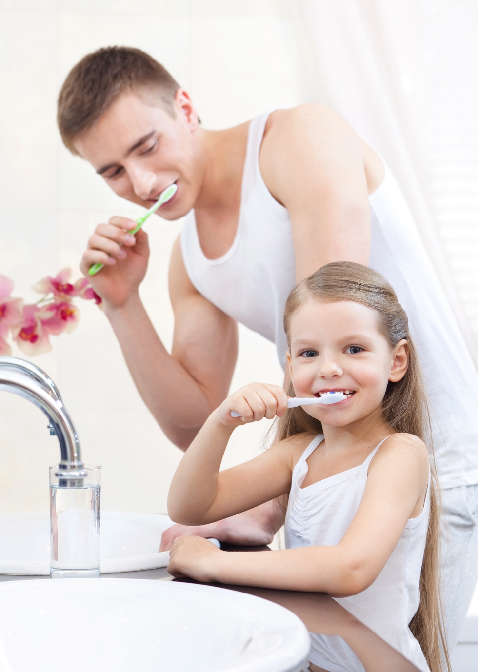 Little girl cleans teeth with her father