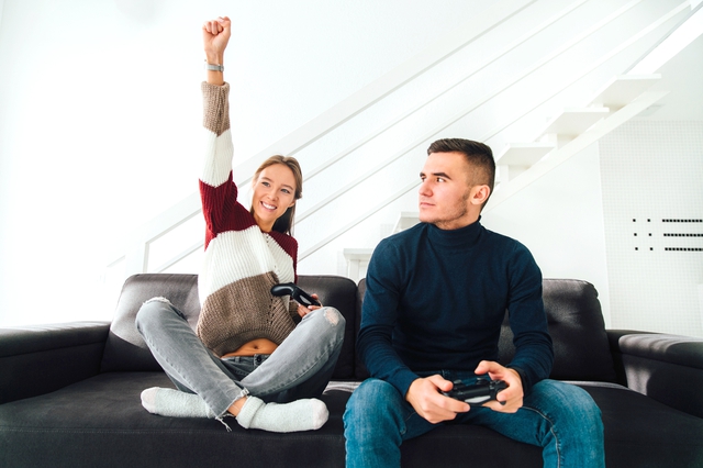 Happy girl showing winning gesture after playing computer games